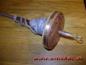 spindel af træ med en skive i den nederste ende; holdes i hånden under spinding