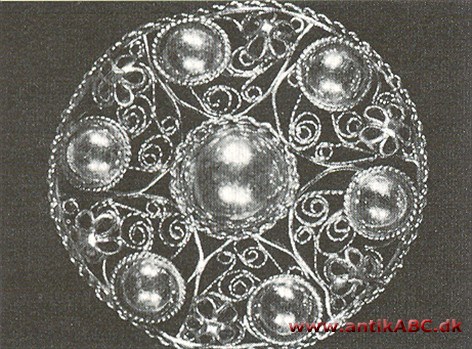  sammenflettede sølv- eller guldtråde, ofte besat med små metalkorn, og anvendt til smykker
